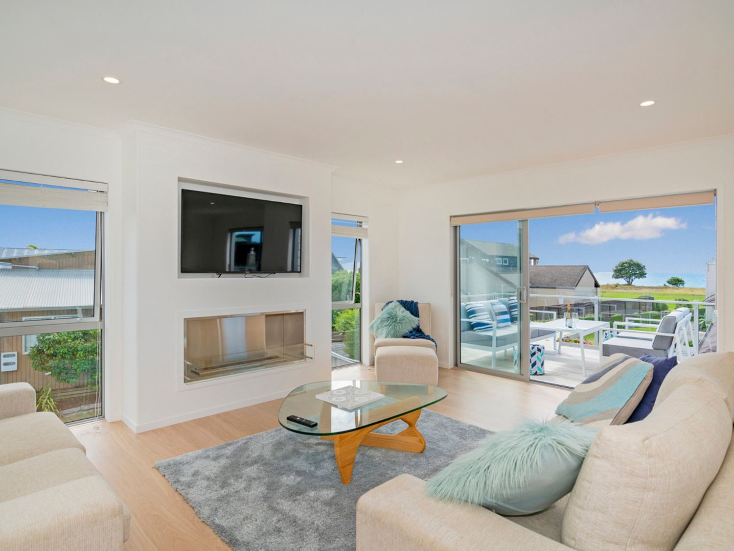 Open living room with fireplace at Coastal Pearl Matarangi — calm coastal interior